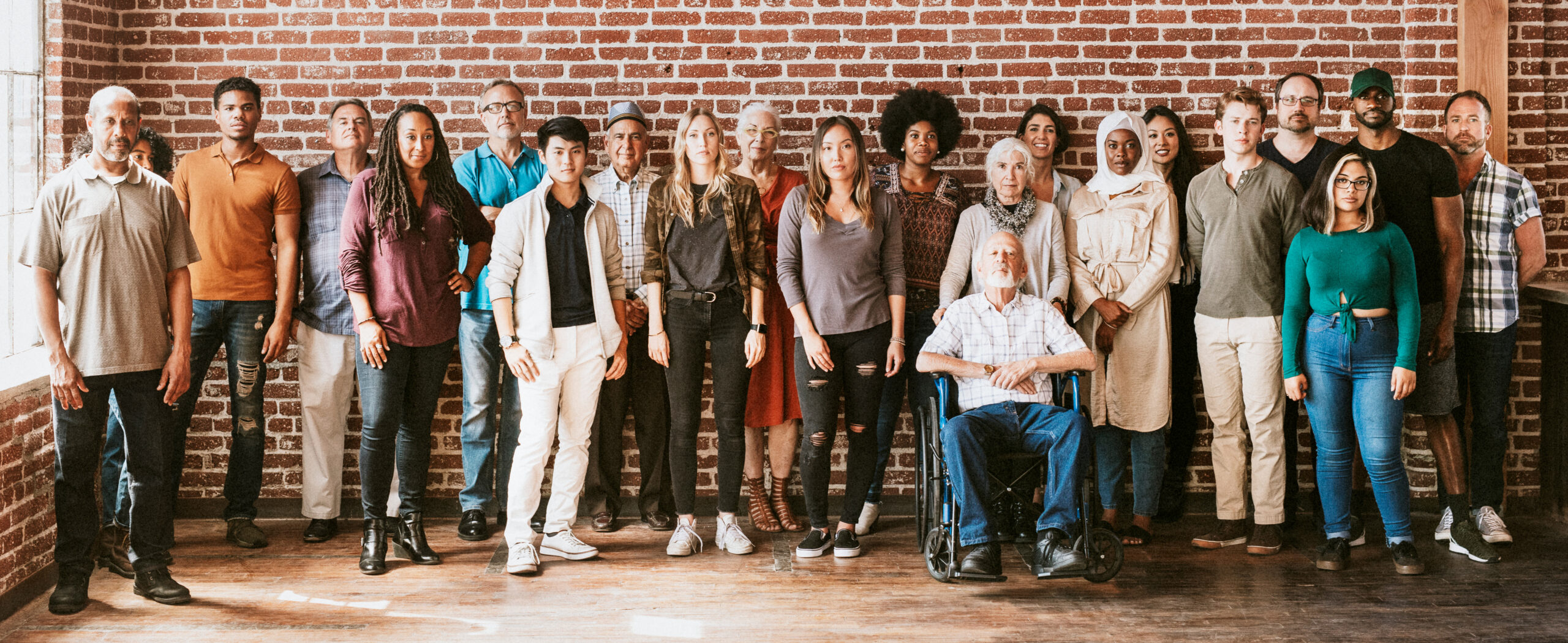 Group of diverse people standing in front of a brick wall