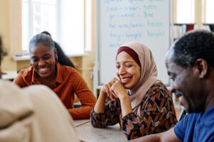 Group of modern immigrants sitting at table having fun laughing.